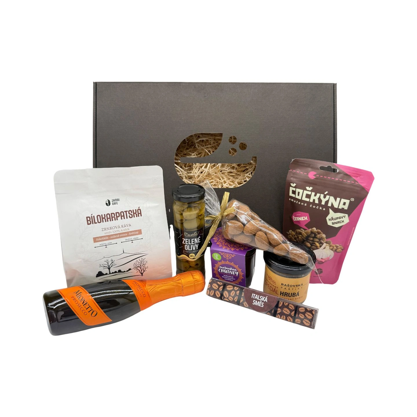 Dárkový gurmánský balíček s kávou Bílokarpatská, lahví prosecca Mionetto, zelenými olivami, sklenicí hrubozrnné hořčice, cibulovým chutney, sáčkem křupavého snacku ČoCkýna a balením ořechů před černou dárkovou krabicí.