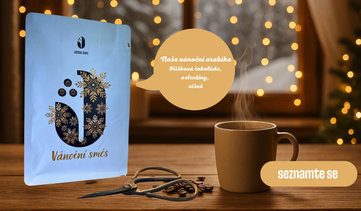 Vánoční kávová směs Jamai Cafe, sáček na stole s šálkem horké kávy a zimními světýlky v pozadí, text Naše vánoční arabika lísková čokoláda, ostružiny, višně a tlačítko Seznamte se